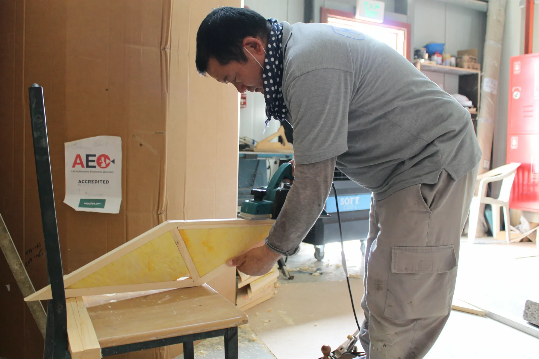 KTS technician building a timber acoustic panel frame around a fibreglass core at the KTS Acoustic Studio workshop in Doha, Qatar